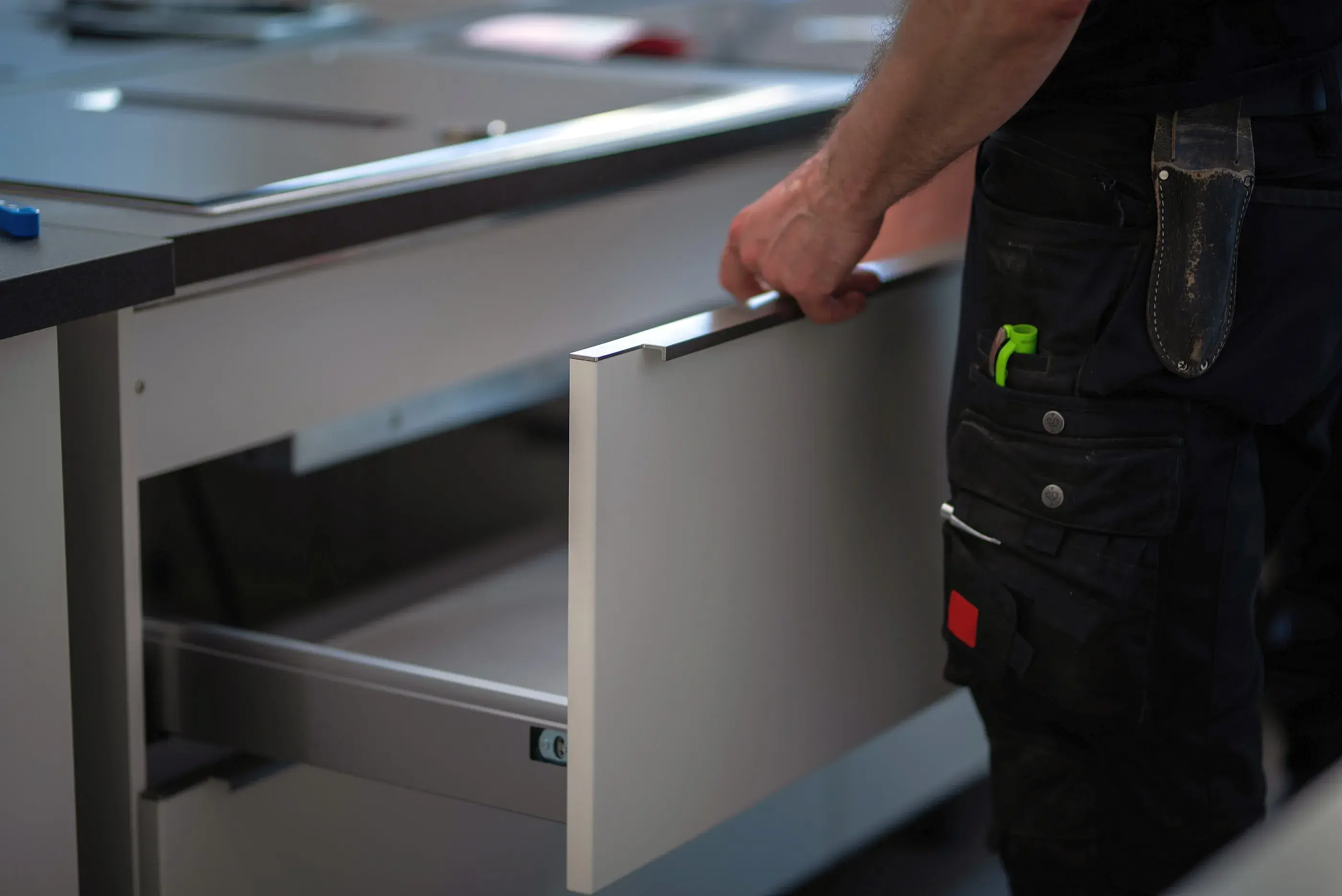 Hand öffnet eine Schublade in einer modernen Küchenzeile.