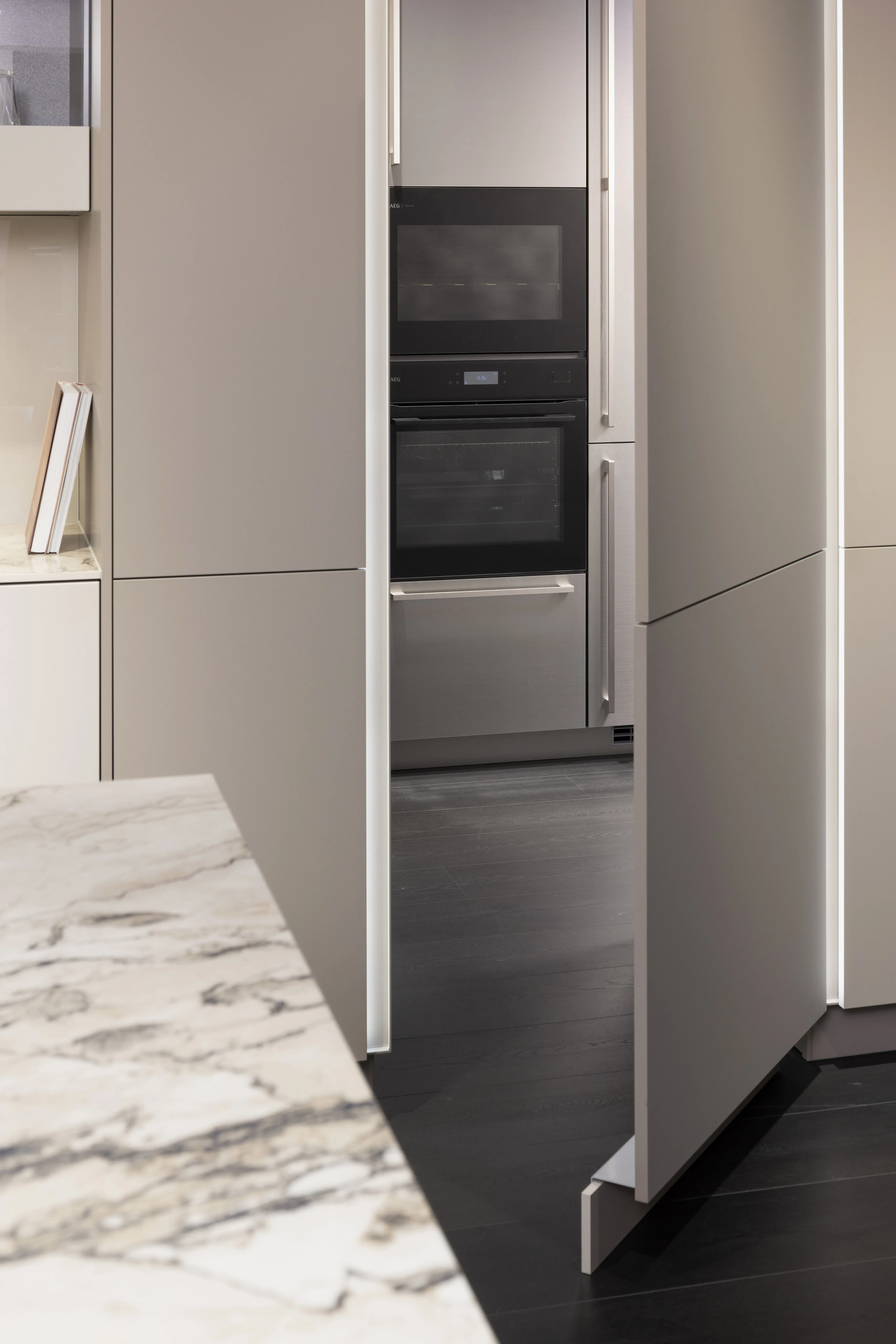 Moderne Küche mit Marmortheke und offener Durchgangstür, Backofen sichtbar.