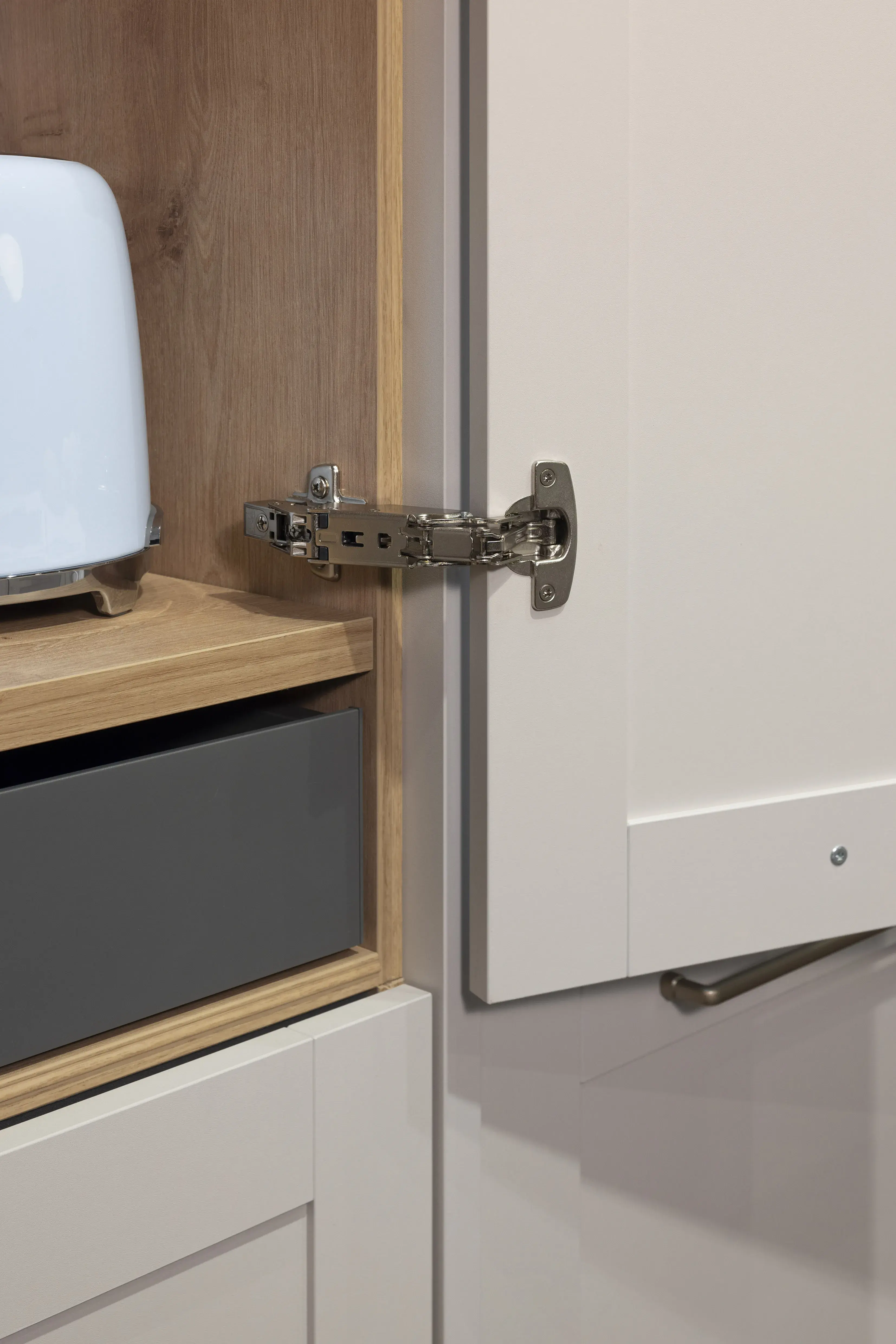 Offener Küchenschrank mit sichtbarem Metallscharnier und weißer Tür.